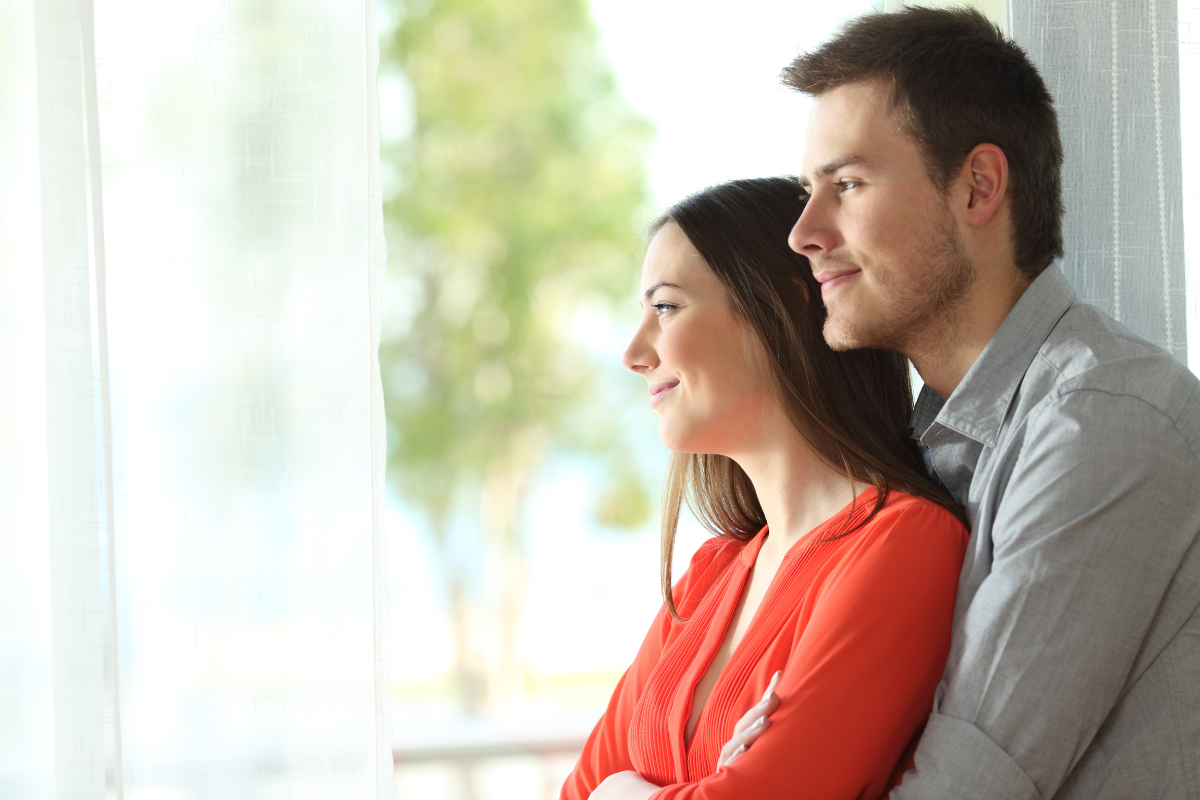 male/female couple embracing by a window