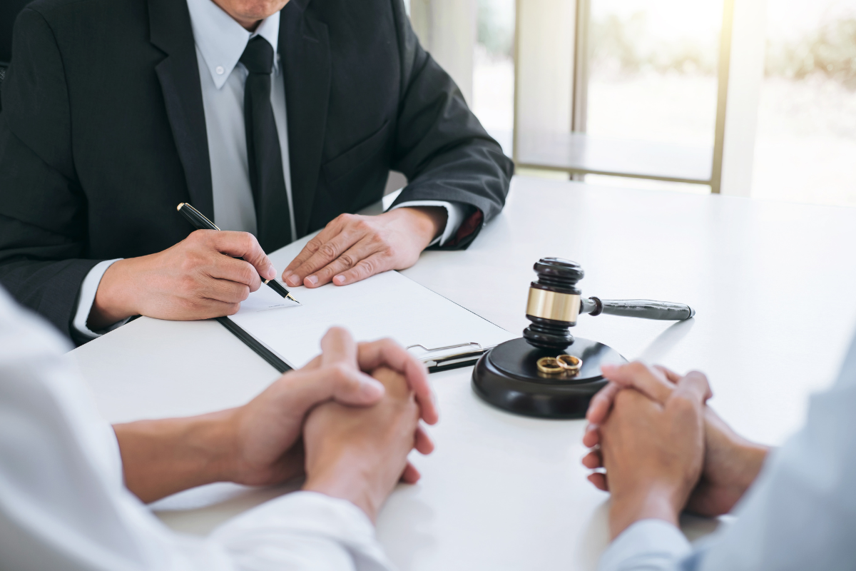 couple meeting with lawyer with papers, gavel, and wedding rings on the table
