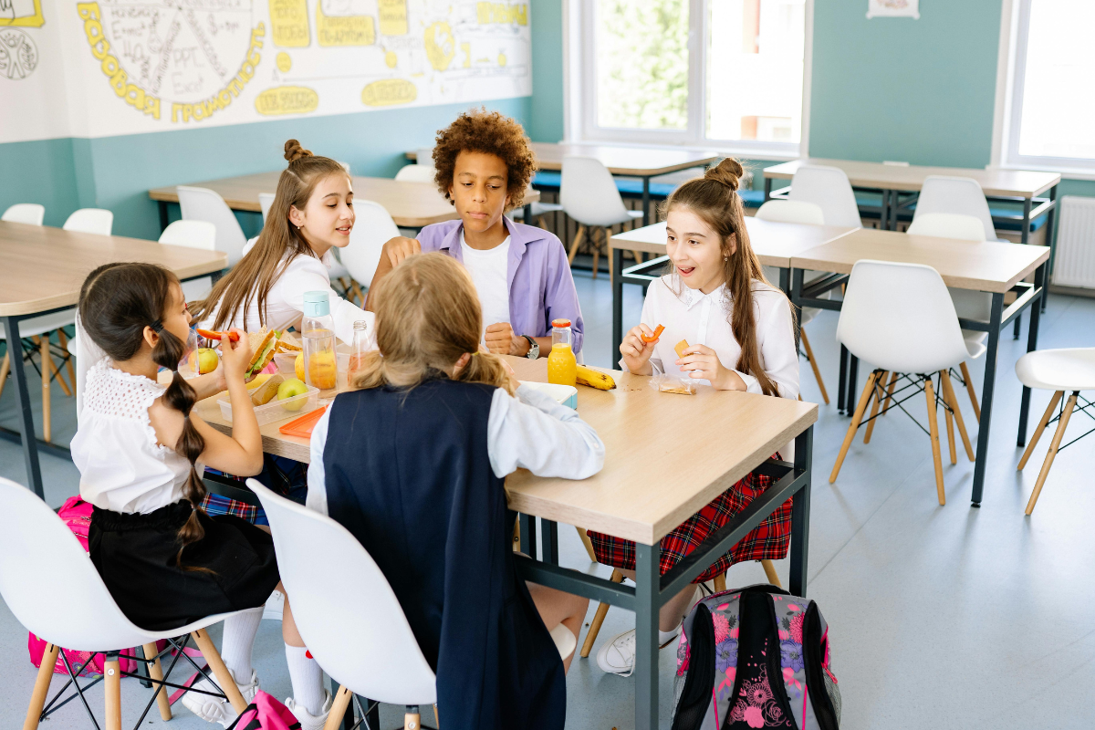 group of kids in school uniforms sitting around a table in a classroom