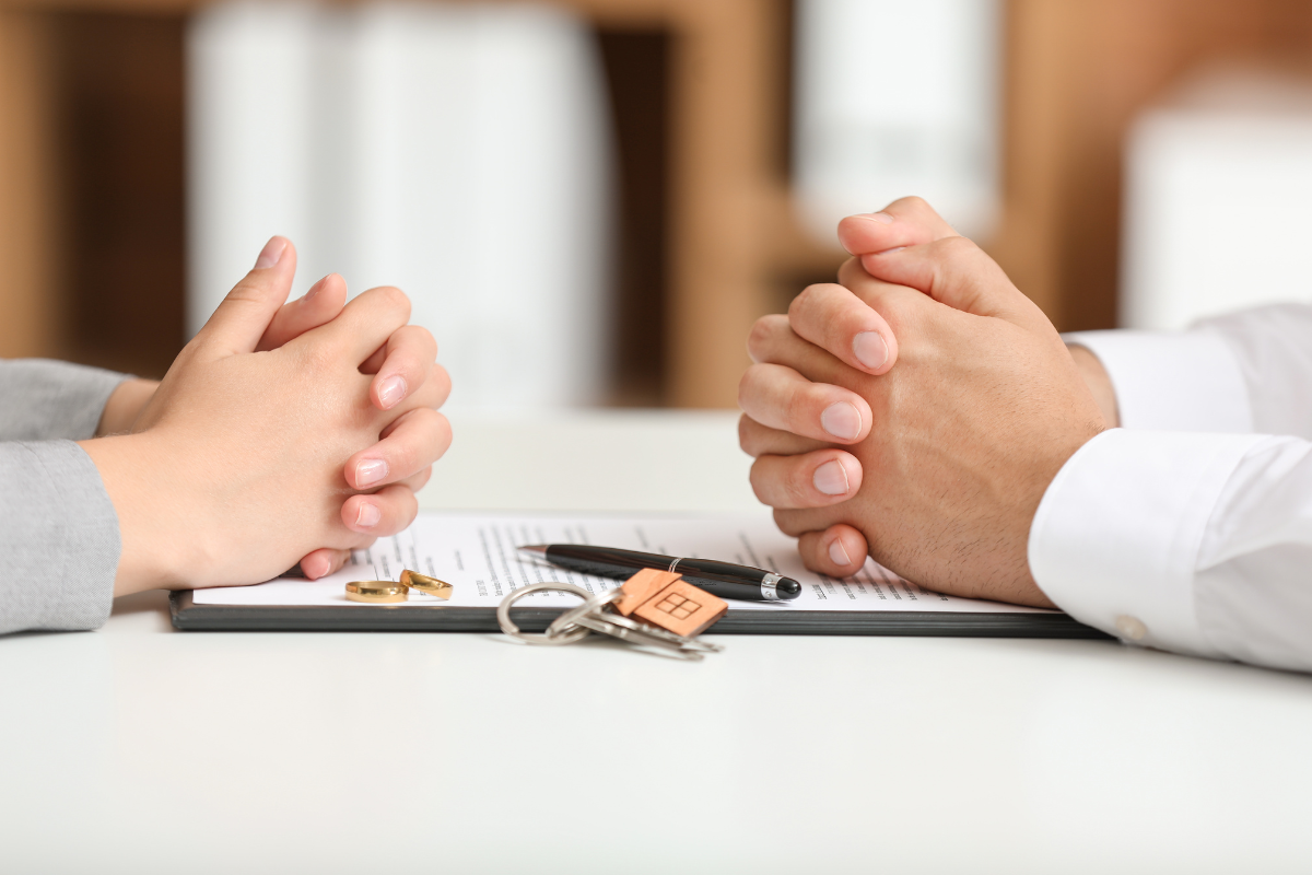 How to Prepare for Divorce Mediation Tips From Our Family Law Attorneys man and woman sitting opposite eachother with their hands crossed with papers and keys between them